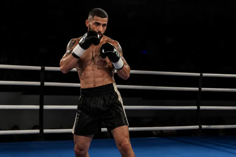 Combattante en tenue de sport adoptant une garde défensive précise au centre d'un ring de boxe.