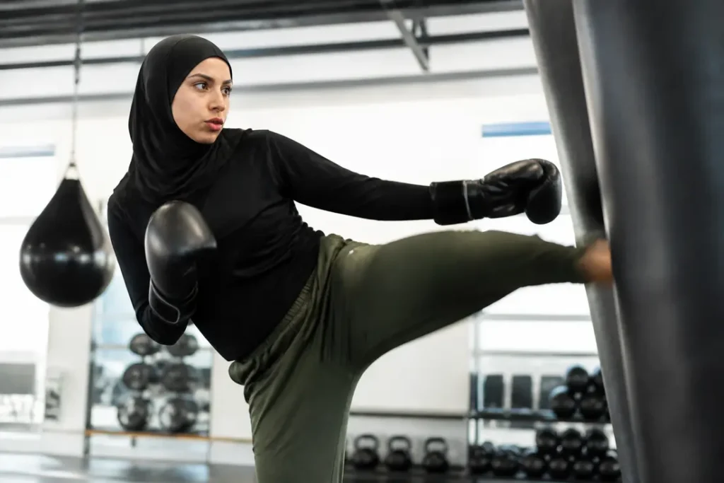 Anissa Meksen effectuant une série d'exercices intenses sur un sac de frappe en salle