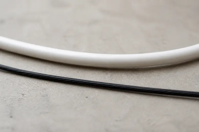 Comparaison visuelle de câbles de corde à sauter : un fin câble en acier gainé et une corde plus épaisse en PVC.