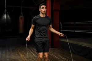 Un jeune boxeur s'entraîne avec une corde à sauter boxe dans un gymnase réaliste en France.