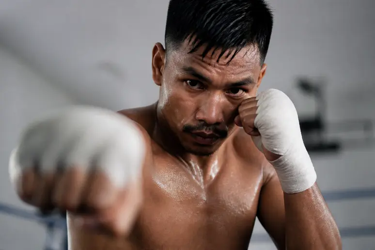 Un combattant de haut niveau exécute une série de mouvements de boxe dans le vide, les mains protégées par des bandes.
