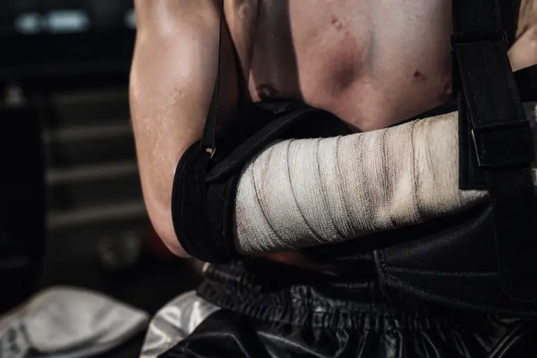 Avant-bras d'un combattant de K-1 bandé et soutenu par une attelle médicale après une blessure.