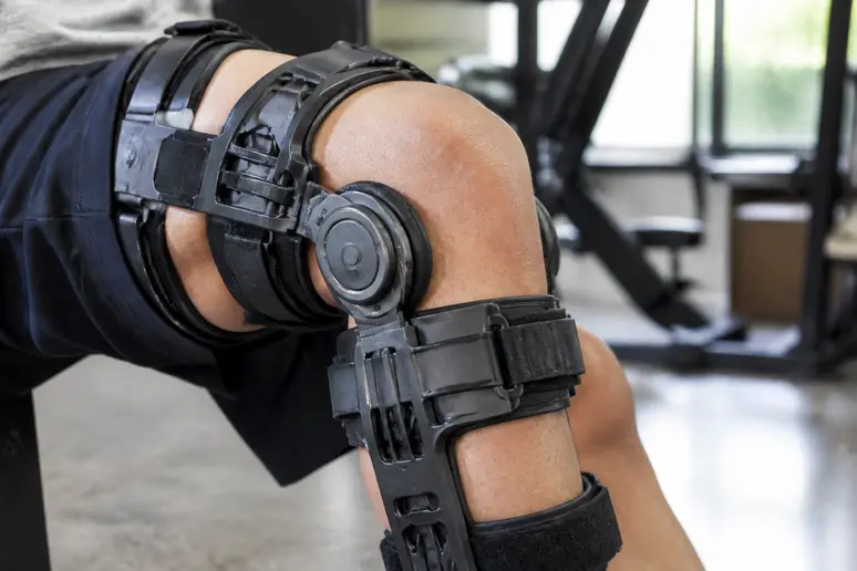 Une genouillère articulée renforce l'articulation du genou durant une séance de rééducation musculaire.