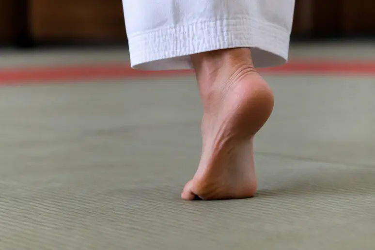 Pied d'appui pivotant sur les coussinets plantaires avec le talon orienté vers l'extérieur sur un tatami.
