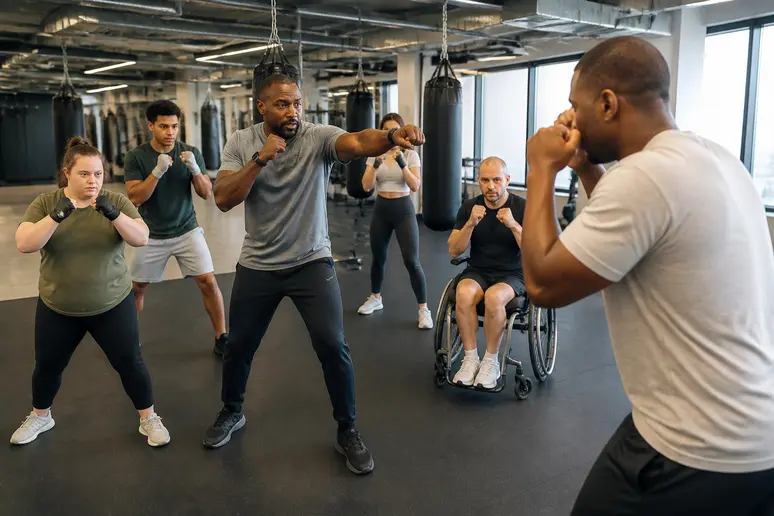 Entraîneur corrigeant la posture d'un groupe diversifié dans une salle de boxe inclusive.