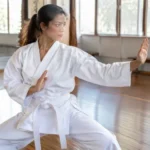 Pratiquant de karaté en kimono blanc réalisant un mouvement technique du kata heian sandan dans un dojo lumineux