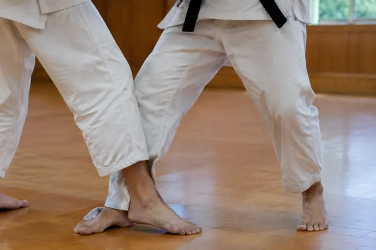 Judoka plaquant son pied gauche parallèlement à celui de son partenaire pour le ko-soto-gari