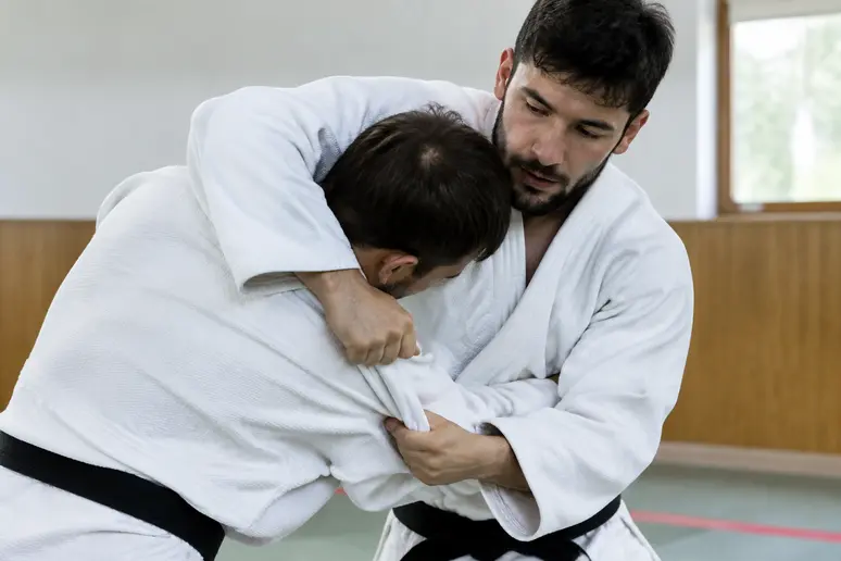 Judoka maintenant fermement le bras autour de la tête pour réussir son koshi guruma.