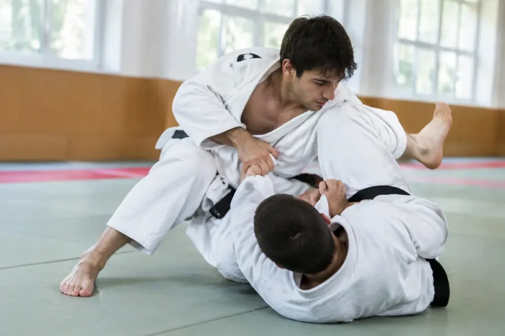 Deux pratiquants en kimono blanc s'entraînent au sol en ne waza sur un tatami de dojo