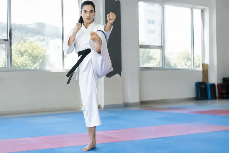 Pratiquant de arts martiaux exécutant un front kick avec les hanches de face dans un dojo