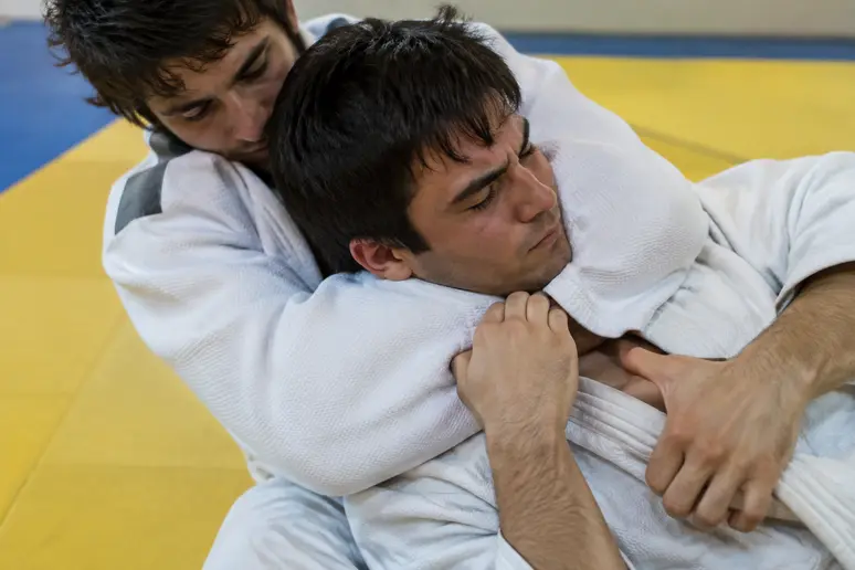 Judoka positionnant son avant-bras sous le menton pour exécuter un hadaka jime sur son partenaire