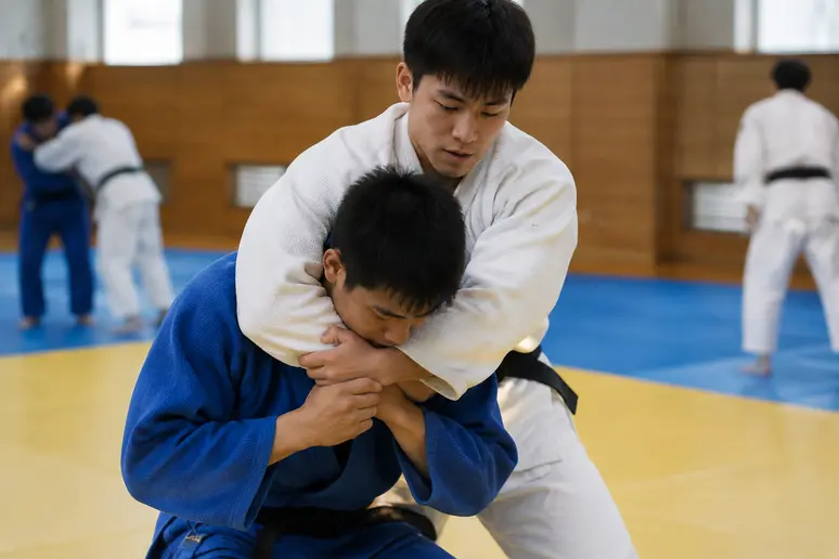 Judoka luttant pour placer un hadaka jime face à une défense solide rentrant le menton