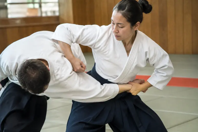 Pratiquant plaquant son bassin pour engager un tomoe nage sur le tatami