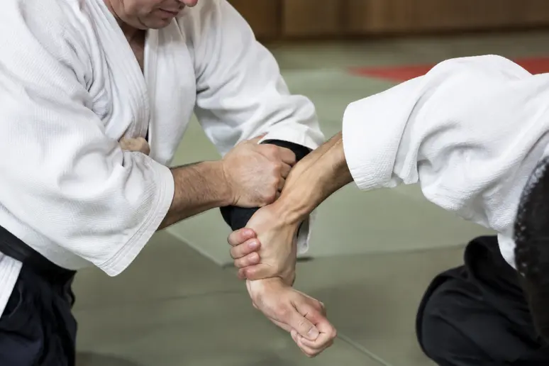 Pratiquant de judo exécutant la rotation de l'ude-garami bras levé sur un tatami.