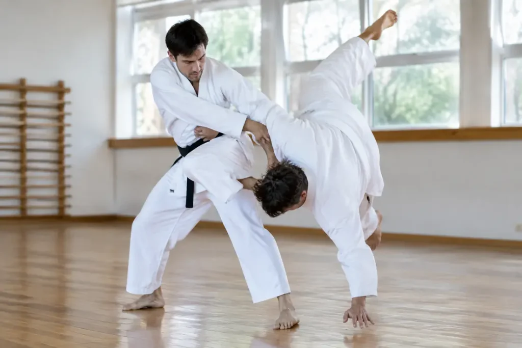 Deux pratiquants en kimono blanc exécutent la technique de projection uki otoshi sur un tatami de dojo.